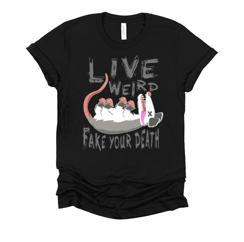Op de afbeelding: Zwart T-shirt met een grijze afbeelding van een opossum met de tekst "Live Weird Fake Your Death" erop.
