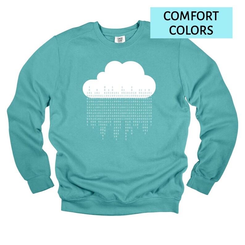 Op de afbeelding: Tealkleurige sweatshirt met een witte wolkengrafiek met binaire code. De tekst "COMFORT COLORS" staat in een lichtblauwe rechthoek. De sweatshirt heeft lange mouwen en een ronde hals.