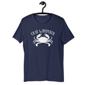 May include: A navy blue t-shirt with a white crab and the text "CRAB WHISPERER" printed on the front.