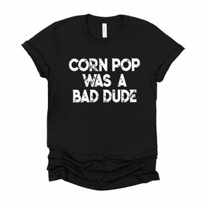 May include: Black t-shirt with white text that reads "Corn Pop was a bad dude".