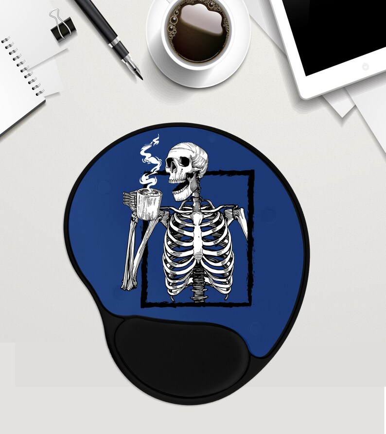May include: A blue round mouse mat with a black skeleton holding a cup of coffee. The skeleton is inside a white square frame. The mouse mat has a black, ergonomic wrist rest.