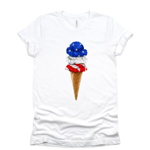 May include: White t-shirt with a graphic of an ice cream cone with red, white, and blue ice cream, resembling the American flag.
