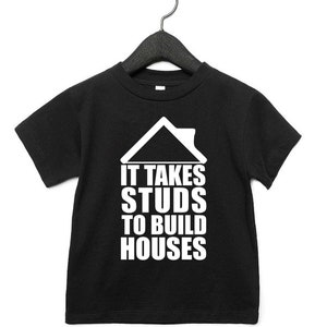 May include: Black t-shirt with a white graphic of a house and the text "It takes studs to build houses".