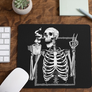 May include: Black and white illustration of a skeleton holding a cup of coffee and giving a peace sign. The skeleton is sitting in a chair and has a relaxed expression on its face. The background is black.