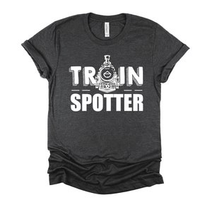 May include: A dark heather gray t-shirt with a white graphic of a train engine and the text "TRAIN SPOTTER".