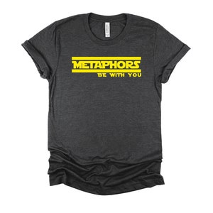 May include: A dark gray t-shirt with yellow text that reads "Metaphors Be With You".