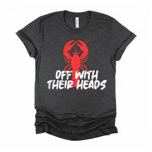 K&ouml;nnte beinhalten: Ein dunkel-helles graues T-Shirt mit einem roten Hummer-Motiv und dem Text "Off with their heads" in Wei&szlig;.