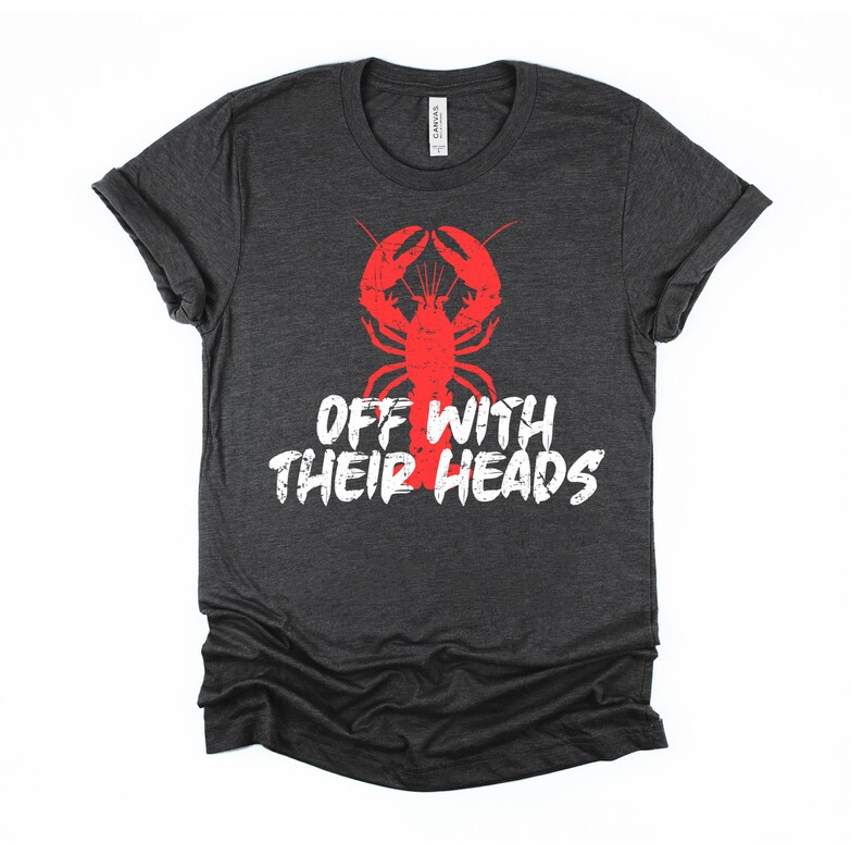 K&ouml;nnte beinhalten: Ein dunkel-helles graues T-Shirt mit einem roten Hummer-Motiv und dem Text "Off with their heads" in Wei&szlig;.