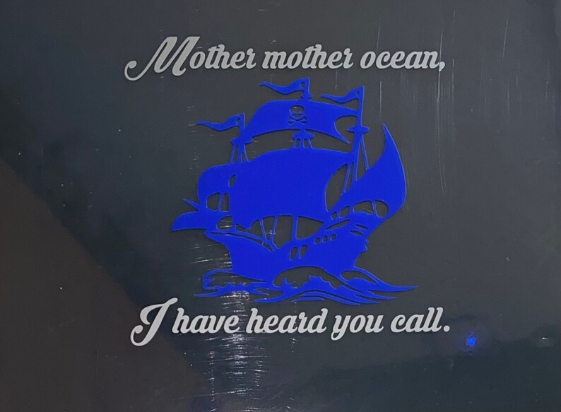 May include: A blue silhouette of a pirate ship with a skull and crossbones on the sail. The text "Mother mother ocean, I have heard you call." is written in white below the ship.