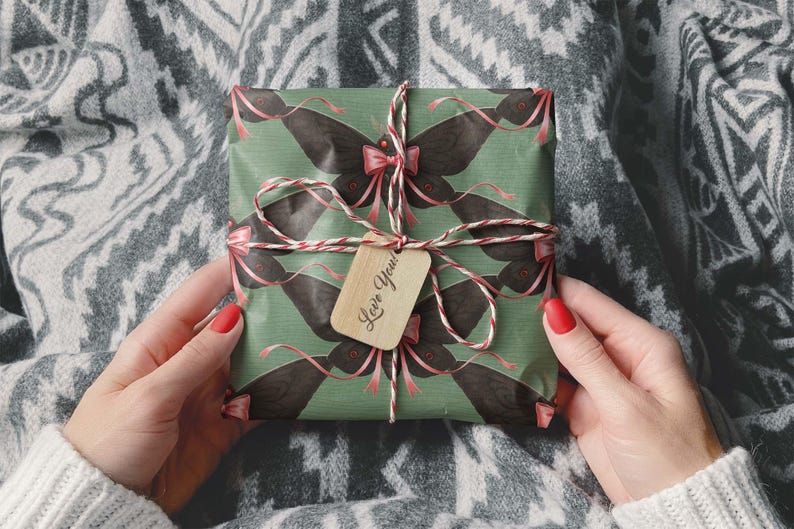 May include: A wrapped gift with a green background and a repeating black butterfly pattern. The gift is tied with a red and white string and a small wooden tag that says "Love You!".