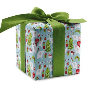 May include: A wrapped gift box with a light blue background featuring a pattern of white elephants, Christmas trees, and gift boxes. The box is tied with a wide green ribbon and bow. The text "Merry Christmas" is visible on the wrapping paper.