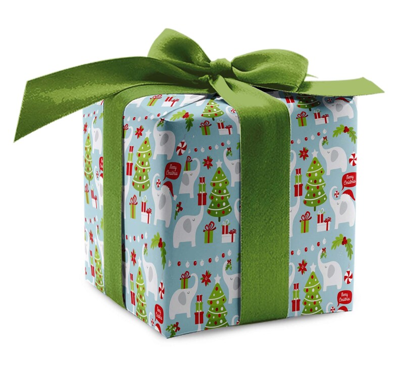 May include: A wrapped gift box with a light blue background featuring a pattern of white elephants, Christmas trees, and gift boxes. The box is tied with a wide green ribbon and bow. The text "Merry Christmas" is visible on the wrapping paper.