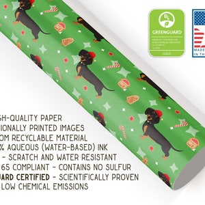 K&ouml;nnte beinhalten: Gr&uuml;nes Geschenkpapier mit einem sich wiederholenden Muster aus Dackeln mit Weihnachtsm&uuml;tzen, Lebkuchenh&auml;usern, Zuckerstangen und Sternen. Hergestellt in den USA und Greenguard-zertifiziert.