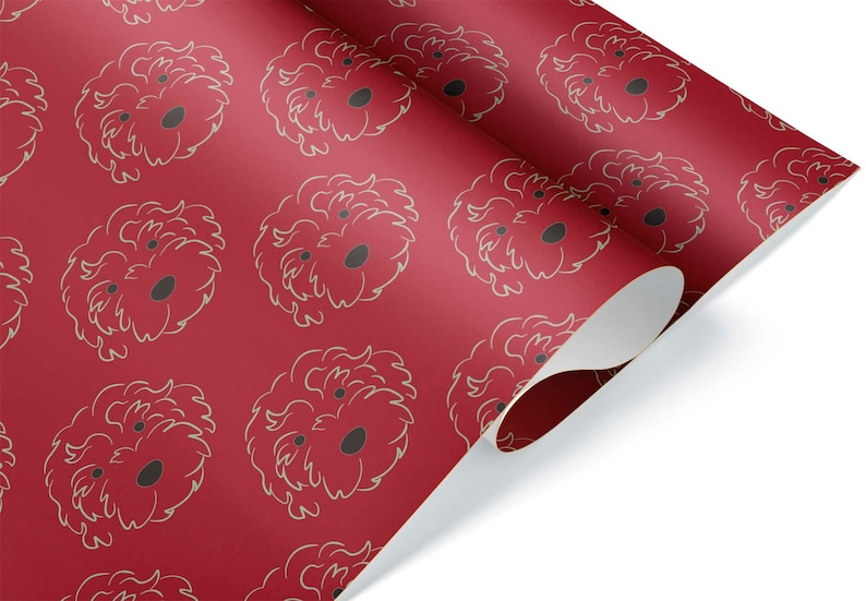 May include: Red wrapping paper with a repeating pattern of a dog's face. The dog's face is outlined in a light beige color, with a dark gray nose and eyes. The paper is partially rolled, revealing the white underside.