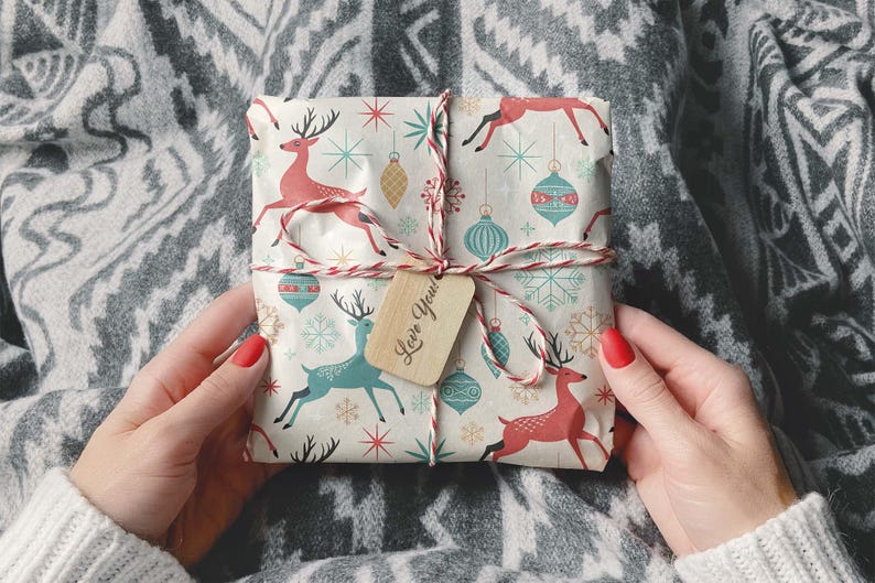 May include: A wrapped gift with a festive pattern featuring red and teal reindeer, ornaments, and snowflakes. The gift is tied with red and white twine and a small tag that says "Love You!"