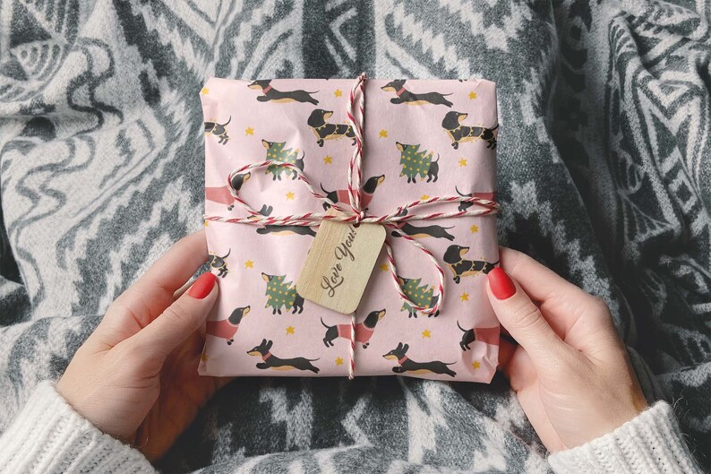 Op de afbeelding: Een roze cadeaudoos verpakt in papier met een teckelpatroon. De doos is vastgebonden met touw en heeft een houten cadeaulabel met de tekst "Love You!"