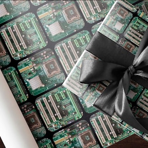 May include: A wrapped gift with a black satin bow. The wrapping paper features a repeating pattern of green and gold computer circuit boards on a black background. A roll of white paper is visible on the left.