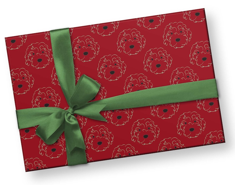 May include: A wrapped gift with red wrapping paper featuring a repeating pattern of dog faces in a light color. A green ribbon is tied around the gift in a bow.