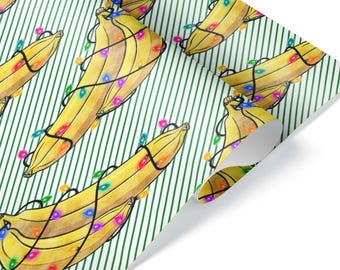 Può includere: Carta da regalo con un motivo ripetitivo di banane gialle avvolte da luci colorate su uno sfondo a sottili strisce diagonali verdi. Lo stile dell'illustrazione è simile all'acquerello con tonalità vivaci.