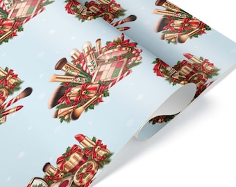 Può includere: Un rotolo di carta da regalo azzurro con un motivo ripetuto di articoli per il trucco, tra cui pennelli, rossetti e palette, decorato con fiocchi rossi, rami di pino verdi, bastoncini di zucchero e piccoli fiocchi di neve.
