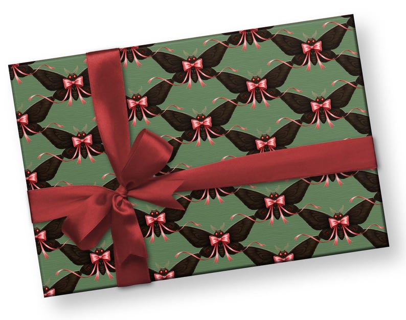 May include: A wrapped gift box featuring a repeating pattern of black moths with pink bows on a green background. The box is tied with a wide, dark red satin ribbon and bow, creating a festive presentation.