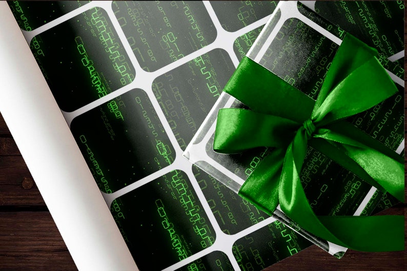 Peut inclure: Un cadeau emball&eacute; avec un ruban vert en satin. Le papier d'emballage a un fond noir avec un motif de grille blanche et des motifs verts ressemblant &agrave; des codes num&eacute;riques. Un rouleau de papier d'emballage assorti est visible.