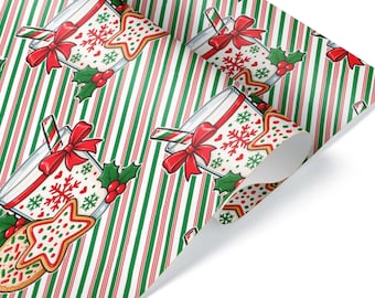 Può includere: Carta da regalo con un motivo ripetitivo di bicchieri pieni di latte, fiocchi rossi, cannucce a bastoncino di zucchero, fiocchi di neve verdi e biscotti a forma di stella su uno sfondo di sottili strisce verticali rosse, bianche e verdi.