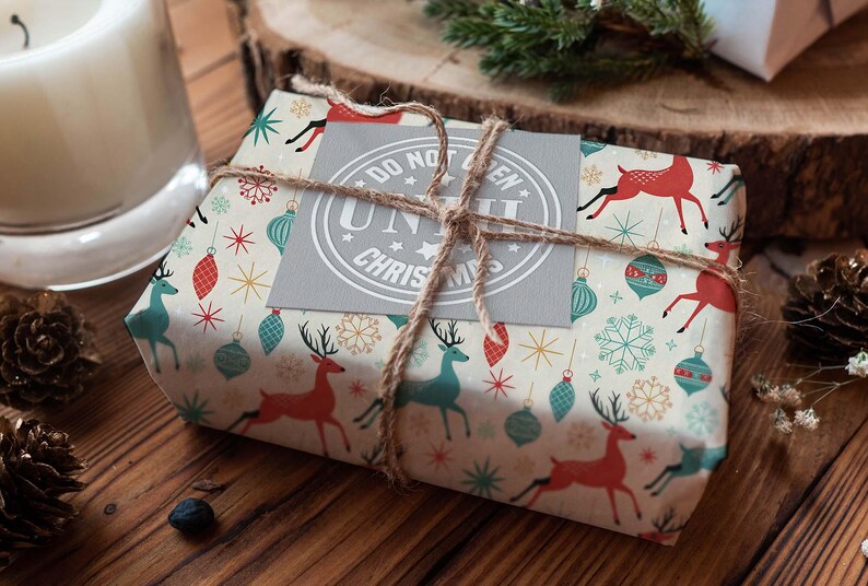 May include: A wrapped gift with festive Christmas-themed paper featuring red and teal reindeer, ornaments, and snowflakes. The package is tied with twine and a gray tag that reads "DO NOT OPEN UNTIL CHRISTMAS".