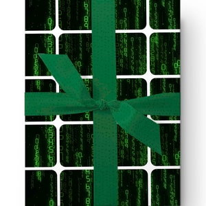 Peut inclure: Un cadeau emball&eacute; avec un ruban vert. Le papier d'emballage pr&eacute;sente un motif de type matrice de chiffres et symboles verts sur fond noir, encadr&eacute; de rectangles blancs. Le ruban vert est nou&eacute; en un n&oelig;ud.