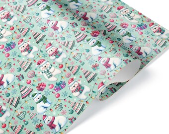 Può includere: Un rotolo di carta da regalo con sfondo verde menta chiaro caratterizzato da un motivo ripetuto di orsi polari bianchi con sciarpe e cappelli colorati, alberi di Natale decorati, pacchetti regalo, palline e luci natalizie.