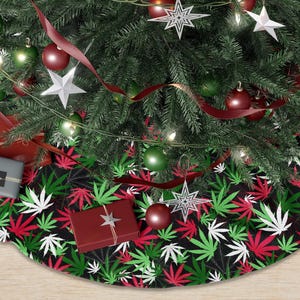 May include: A Christmas tree skirt with a black background and a pattern of red, green, and white cannabis leaves. The skirt is under a decorated Christmas tree with ornaments and presents.