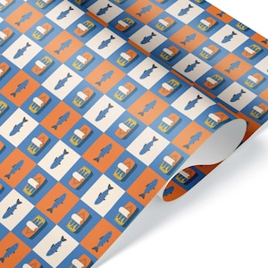 May include: A roll of wrapping paper featuring a repeating grid pattern of alternating orange and white squares. The orange squares contain illustrations of blue fish, while the white squares feature illustrations of open sardine tins.