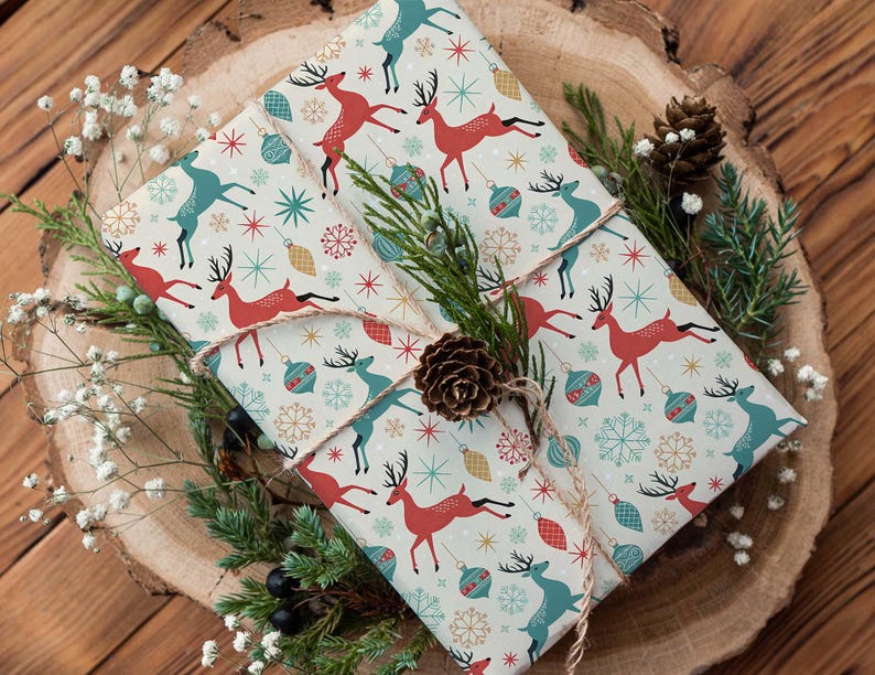 May include: Two wrapped gifts with festive wrapping paper featuring red and teal reindeer, snowflakes, and ornaments. The gifts are tied with twine and decorated with pine, berries, and a pinecone, set on a wooden surface.