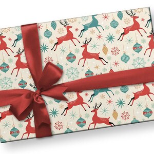 May include: A rectangular gift box wrapped in cream-colored paper with a festive pattern of red reindeer, teal ornaments, and snowflakes. A wide, red satin ribbon is tied around the box in a bow.