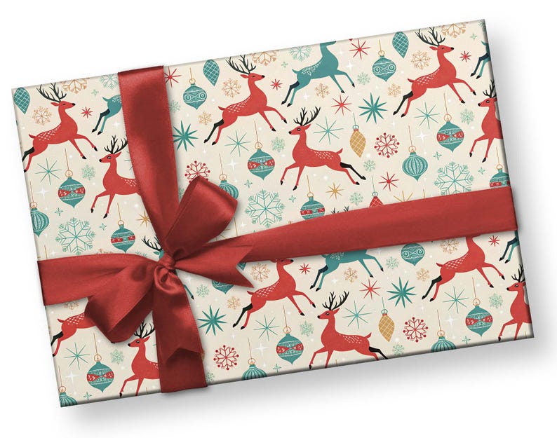 May include: A rectangular gift box wrapped in cream-colored paper with a festive pattern of red reindeer, teal ornaments, and snowflakes. A wide, red satin ribbon is tied around the box in a bow.
