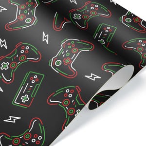 May include: Black wrapping paper with a repeating pattern of video game controllers and lightning bolts in red, green, and white. The controllers are outlined with a neon effect.