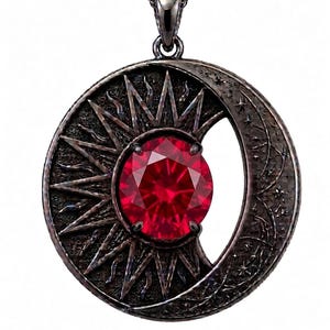 Peut inclure: Un pendentif en métal sombre avec un motif circulaire combinant un soleil rayonnant d'un côté et un croissant de lune avec des étoiles gravées de l'autre. Une grande pierre précieuse rouge ronde et facettée est sertie au centre.