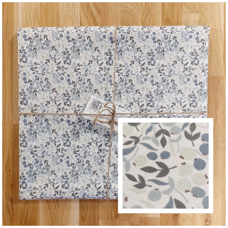 May include: A gift wrapped in white wrapping paper with a blue and gray floral pattern. The paper is tied with twine and a small tag that says "A.J. Studio".
