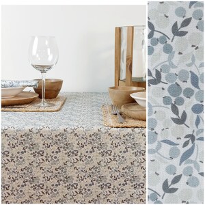 May include: A beige tablecloth with a blue and brown floral pattern. The tablecloth is set with a glass wine glass, wooden bowls, and plates. The tablecloth is made of a soft, durable fabric and is perfect for everyday use.