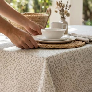 Könnte beinhalten: Ein gedeckter Tisch mit einer weißen Schüssel, einem Teller und einer Tasse. Die Artikel befinden sich auf einem gewebten Platzset und einer Tischdecke mit Blättermuster. Ein Weidenkorb und eine Vase mit getrockneten Blumen sind im Hintergrund.