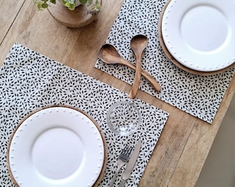 Coated cotton placemats with green foliage on an ecru background.