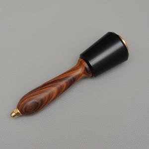 May include: A wooden mallet with a black rubber head and a brass band. The handle is made of dark wood with a striped pattern.