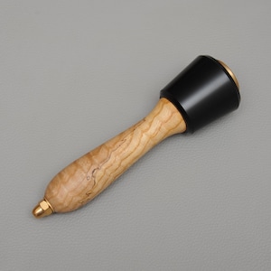 May include: A wooden mallet with a black rubber head and a brass tip. The handle is made of wood with a natural grain pattern.