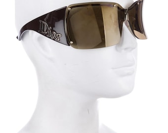 Peut inclure: Lunettes de soleil en plastique marron avec des accents dorés et des verres miroir marrons. Les lunettes portent l'inscription "Dior" sur le côté.