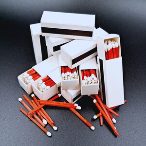 Handgeselecteerde witte luciferdoosjes voor bruiloften of feesten worden geleverd in sets van 10. Elke lucifer heeft een sluitstuk en bevat 24 lucifers van rood hout met witte tips