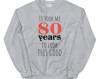 May include: A gray sweatshirt with the text "It took me 80 years to look this good" printed on the front. The number 80 is in red.