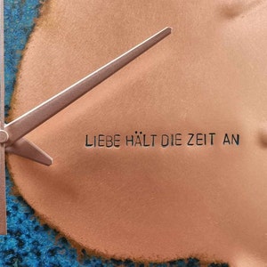 A close up image of the Blue Patina Copper Wall Clock with the engraving LIEBE HALT DIE ZEIT AN which translates to Love Stops Time. The clock is made by Copper, Brass and Bronze and Empire Copper by Hayes Home.