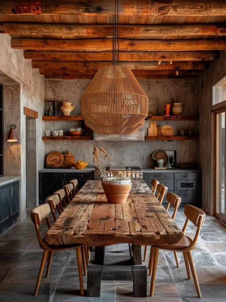 May include: A rustic dining room featuring a large, weathered wooden table with matching chairs. A woven pendant light hangs above the table. The room has exposed wooden beams and stone flooring, creating a warm, inviting atmosphere.