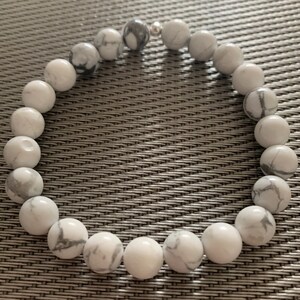 May include: White howlite beaded bracelet with silver accents. The beads are round and have a marbled pattern.