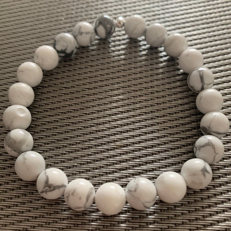 May include: White howlite beaded bracelet with silver accents. The beads are round and have a marbled pattern.